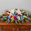 A broad, low-profile casket spray that reads as a dignified salute-white lilies
