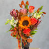 Orange sunflower and roses in a black vase with a plaid ribbon