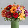 Mixed bouquet of orange, red, and purple flowers in a green vase