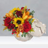 Bouquet of red roses, sunflowers, and orange lilies in a white pumpkin vase