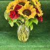 Sunflowers and red roses arranged in a clear glass vase