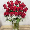 Red roses arranged in a clear glass vase with white baby's breath