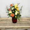 Mixed roses and yellow flowers in a red glass vase