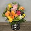 Mixed bouquet with roses, lilies, and carnations in a black vase
