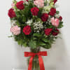 Red roses and pink carnations in a glass vase with a red ribbon