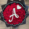 Round arrangement of red roses with a white A initial and heart on top, wrapped in black paper