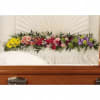 Colorful floral spray arranged across a white casket