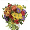 Colorful mixed bouquet in a clear glass vase with a green polka-dot ribbon