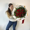 Woman holding a large bouquet of red roses wrapped in white paper