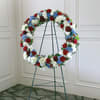 Circular floral wreath on a metal stand with red, white, and blue flowers