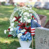 Memorial flower arrangement in a white urn with red, white, and blue flowers
