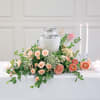 Peach and pink floral centerpiece around a silver urn with candles