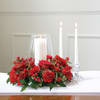 Red floral centerpiece with three white candles in glass holders