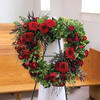 Heart-shaped red rose wreath on a stand with greenery