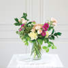 Mixed bouquet of pastel roses and chrysanthemums in a clear glass vase