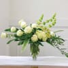 White roses and green flowers in a clear glass vase
