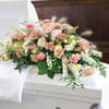 Pastel floral spray on a white casket