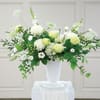 White and pale green floral arrangement in a white vase