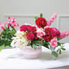 Pink and red floral arrangement in a pale pink vase