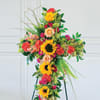 Tall floral cross on a stand with sunflowers, roses, and carnations
