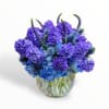 Blue and purple flower arrangement in a clear glass vase