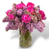 Pink peonies and lilac blooms arranged in a clear glass vase