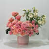 Pink roses and peach carnations in a pink vase with white flowers
