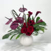 Red roses and burgundy calla lilies in a white vase