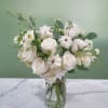 White roses and small white blooms in a clear glass vase