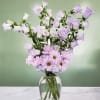 Lavender bellflowers and pink daisies in a clear glass vase
