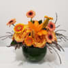 Orange and peach flowers arranged in a green glass vase
