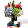 Bouquet of hydrangeas and roses in a glass vase with books underneath