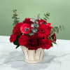 Red flowers arranged in a white wooden basket with silver eucalyptus