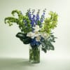 Blue, white, and green floral arrangement in a clear glass vase