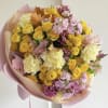 Bouquet of yellow, pink, and cream flowers wrapped in blush paper