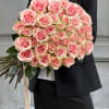 Large bouquet of pink roses held by a person in a black suit