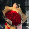 Woman holding a large bouquet of red roses wrapped in brown paper