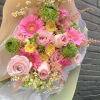 Bouquet of pink roses, gerbera daisies, and green blooms wrapped in paper