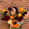 Woman holding a pumpkin filled with colorful flowers