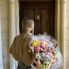 Person holding a large pastel bouquet of mixed flowers