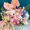 Pink and white bouquet with anthuriums, roses, and calla lilies in a round box