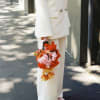 Person in white suit holding a colorful bouquet of pink and orange flowers