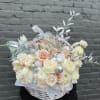 Cream and blush bouquet in a white basket with silver accents