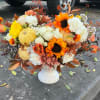 Autumn floral arrangement with sunflowers, white roses, and pumpkins in a white vase