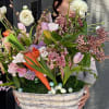 Large spring bouquet in a woven basket with pastel flowers and speckled eggs