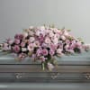 Pink and white floral casket spray on a gray casket