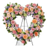 Heart-shaped floral wreath with pink, peach, and lavender blooms on an easel