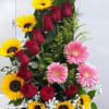 Tall floral arrangement with sunflowers, red roses, and pink gerbera daisies