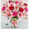 Pink and red mixed bouquet in a clear glass vase with a pink ribbon