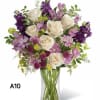 Bouquet of white roses and purple flowers in a clear glass vase